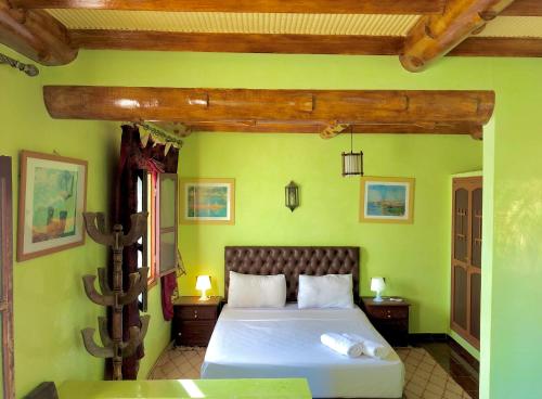 a bedroom with a large bed with green walls at Hotel L'Arganier d'Ammelne in Tafraoute