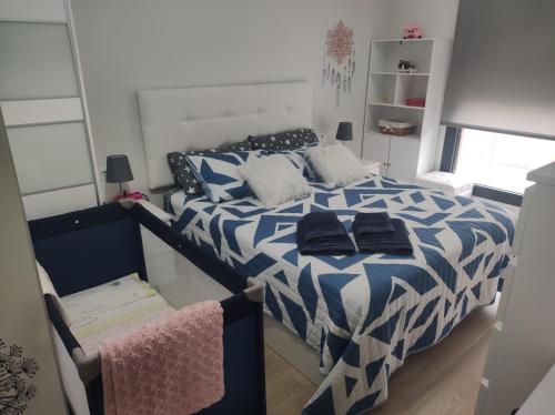 1 dormitorio con 1 cama con edredón azul y blanco en apartamento con jardín privado a 300 metros de la playa, en Soto de la Marina