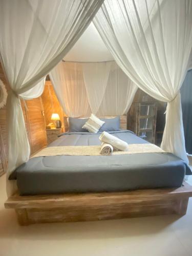 a bed with white curtains and a wooden platform sidx sidx sidx at Batur cottage in Kubupenlokan