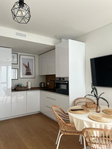 uma cozinha com armários brancos e uma mesa com cadeiras em Jorė em Juodkrantė