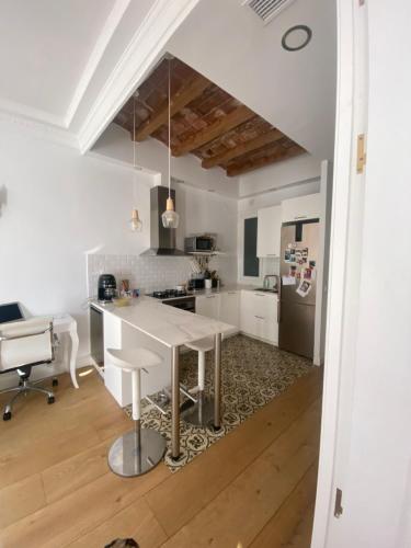 eine weiße Küche mit einem Tisch und einem Kühlschrank in der Unterkunft Apartamento eixample Barcelona in Barcelona