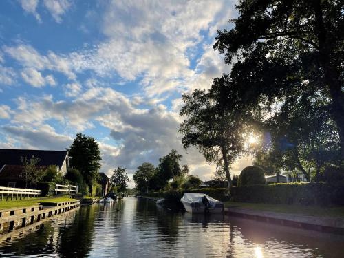 a river with boats in it under a cloudy sky at Camping Kleine Belterwijde, Trekkershut in Belt-Schutsloot