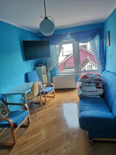 a living room with a blue couch and a table at Pokój Gościnny Gdańska 21 J in Świnoujście