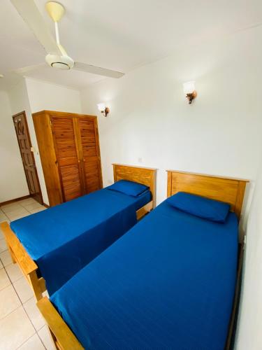 two beds in a room with blue sheets at Oceanic View Apartments in Beau Vallon
