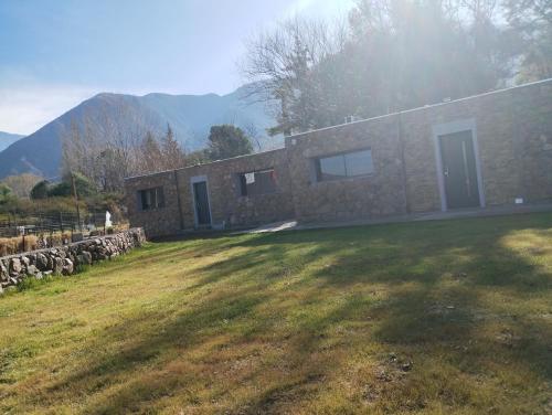 a stone house in a field with mountains in the background at Cabañas Uva in Ciudad Lujan de Cuyo