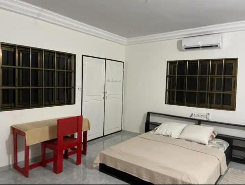 a bedroom with a bed and a desk and windows at Villa Stella in Lomé