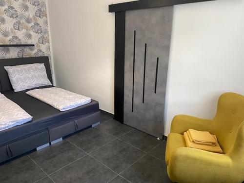 a bedroom with a bed and a yellow chair at Dóra vendégház in Letenye