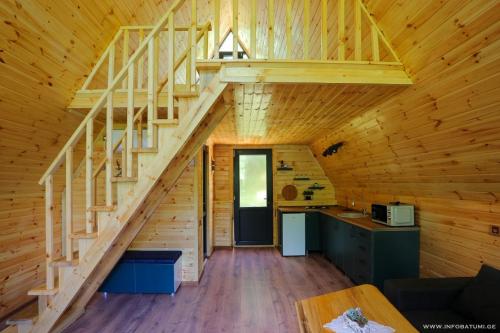 una escalera en una cabaña de madera con cocina en Discover Gulebi, en K'eda