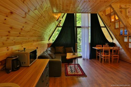 Cabaña con sala de estar con sofá y TV. en Discover Gulebi, en K'eda