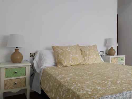 ein Schlafzimmer mit einem Bett mit zwei Nachttischen und zwei Tischen in der Unterkunft Apartamento Vimianzo Sabadelle in Vimianzo