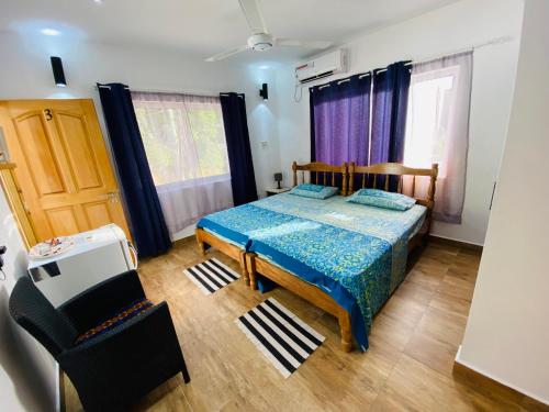 a bedroom with a bed and a chair and windows at Oceanic View Apartments in Beau Vallon