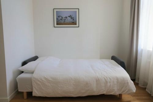 een wit bed in een slaapkamer met een foto aan de muur bij Studio in the city center in Rīga