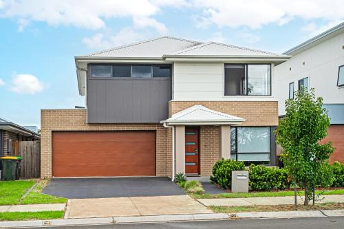 a house with a brown garage at Spacious Modern 5Bedroom Retreat near Gregory Hill in Narellan