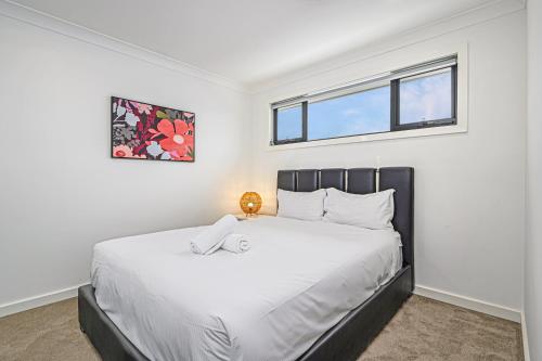 a bedroom with a large white bed with a window at Spacious Modern 5Bedroom Retreat near Gregory Hill in Narellan