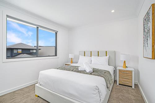 a white bedroom with two beds and a window at Spacious Modern 5Bedroom Retreat near Gregory Hill in Narellan