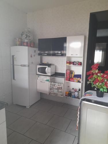 uma cozinha com um frigorífico branco e um micro-ondas em Junior doce lar em Resende