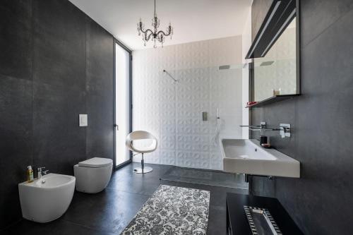 een badkamer met een wastafel, een toilet en een spiegel bij B&B Coccaluto 39 in Castrignano deʼ Greci