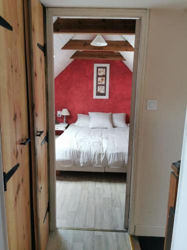 a bedroom with a bed and a red wall at Les gîtes de Blandine in Peumérit