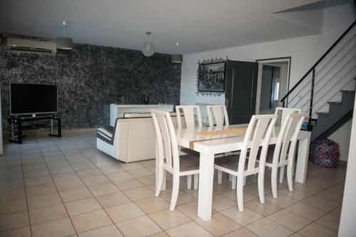a dining room with a white table and chairs at La case à Nath - Piscine chauffée et jacuzzi in Saint-Pierre