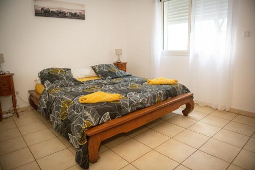 Bett in einem Zimmer mit Fenster in der Unterkunft La case à Nath - Piscine chauffée et jacuzzi in Saint-Pierre