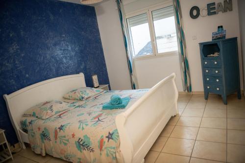 a bedroom with a bed with a blue wall at La case à Nath - Piscine chauffée et jacuzzi in Saint-Pierre