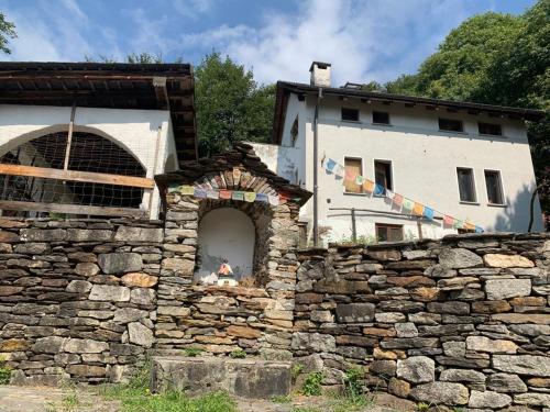 eine Steinmauer mit einem Gebäude im Hintergrund in der Unterkunft Secret Mountain Retreat Valle Cannobina (for nature Lovers only) in Orasso