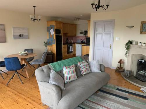 sala de estar con sofá gris y cocina en Roundstone Home with a Harbour and Mountain View, en Roundstone