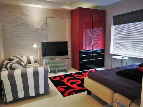 um quarto com uma cama, uma televisão e um sofá em Villa Baneheia em Kristiansand