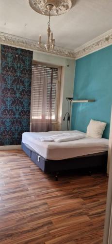 - une chambre avec un lit et un mur bleu dans l'établissement Zimmer in Kaiserslautern, à Kaiserslautern