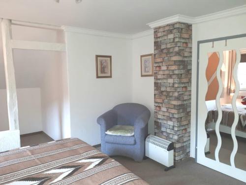 a bedroom with a chair and a brick fireplace at Ferienhaus Peter in Weidenberg