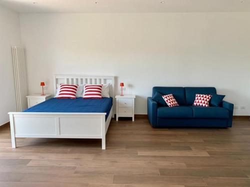 a bedroom with a bed and a blue couch at Due Golfi Apartment in SantʼAgata sui Due Golfi