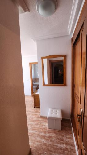 a hallway with a mirror and a stool in a room at La Manga del Mar Menor Los Miradores block 1 5th floor G in Murcia