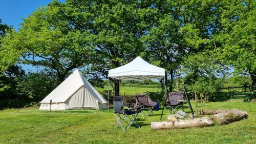 a tent and two chairs in a field at Route 47 Glamping Bell Tents in Cross Hands