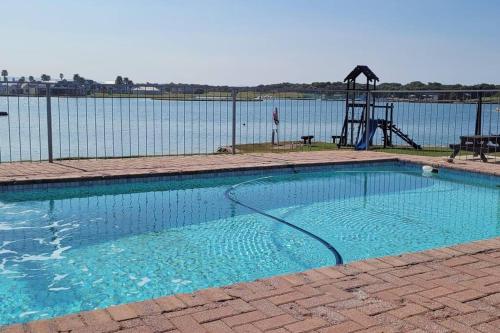 a swimming pool with a playground next to the water at Macs Cove, Marina Martinique in Jeffreys Bay