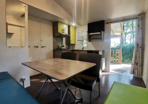 cocina y comedor con mesa y sillas en Mobil Home 6 personnes 3 chambres à 25 MIN Puy duFou en La Boissière-de-Montaigu