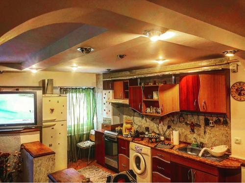 een keuken met een wastafel en een tv. bij Apartament ZEN in Tîrgu Ocna