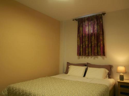 a bedroom with a bed and a window with a curtain at Green Cozy Nest in Paleo Tsifliki