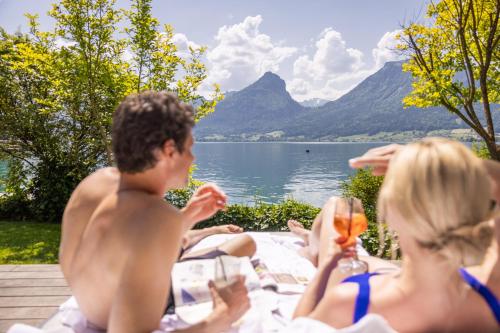 eine Gruppe von Menschen, die auf einem Picknicktisch am Wasser sitzen in der Unterkunft Hotel Seevilla Wolfgangsee in St. Wolfgang