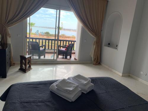 een slaapkamer met 2 handdoeken op een bed en een balkon bij Bord de mer, villa de luxe in Casablanca
