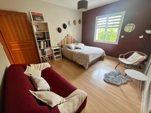 a bedroom with a bed and a couch and a window at La rocaille 3 chambres doubles in Fondettes