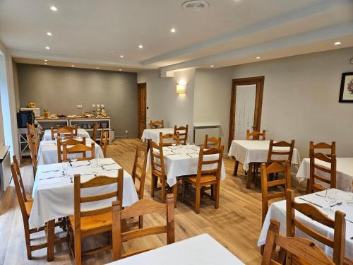 a dining room with white tables and wooden chairs at Hotel Anglada in Vielha