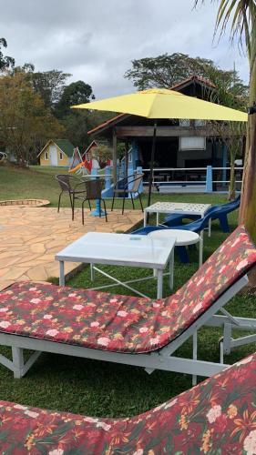 a group of chairs and tables with an umbrella at Pousada Sitio Roda D'Água Mairinque in Mairinque