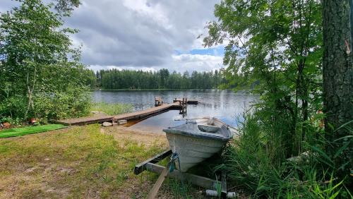 ein Boot am Ufer eines Sees mit einer Anlegestelle in der Unterkunft Villa Helmi in Jämsä