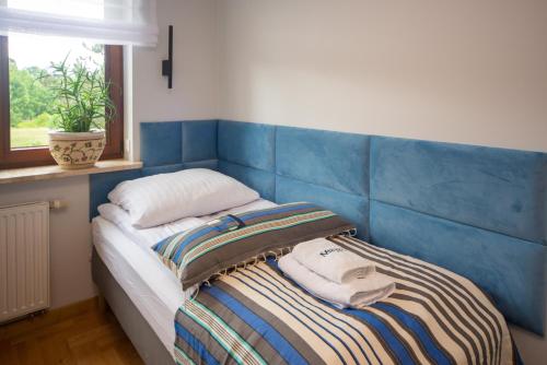 a bed with a blue headboard with two towels on it at Maya's Flats & Resorts 102 - PREMIUM 3 rooms apartment near the sea in Gdańsk