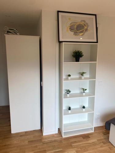 a room with a white book shelf with potted plants at Nice guest house in Stockholm