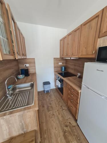 a kitchen with wooden cabinets and a white refrigerator at Elina Apartman in Keszthely