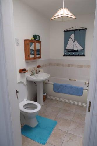 a bathroom with a toilet and a sink and a tub at Obsidian: Arguably the best view in Portballintrae in Portballintrae