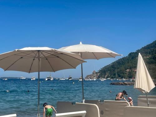 un groupe de personnes assises sur une plage avec des parasols dans l'établissement The Beach House, Theoule sur mer, Cote dAzur, France, à Théoule-sur-Mer