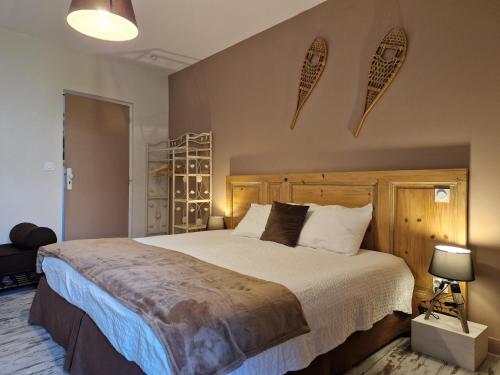 um quarto com uma cama grande e uma cabeceira em madeira em UNE AUTRE MAISON Chambres d'hôtes em Pupillin