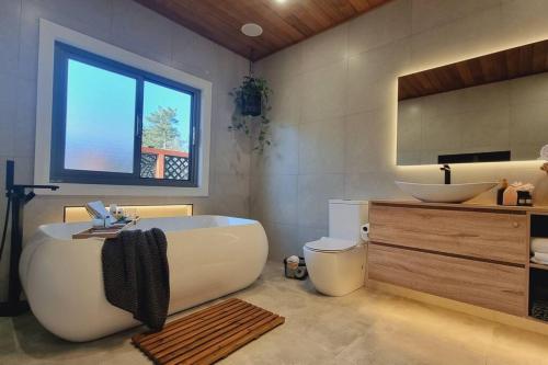 Un baño con bañera, lavabo y espejo. en Blue Mountains Sweet Retreat, en Leura